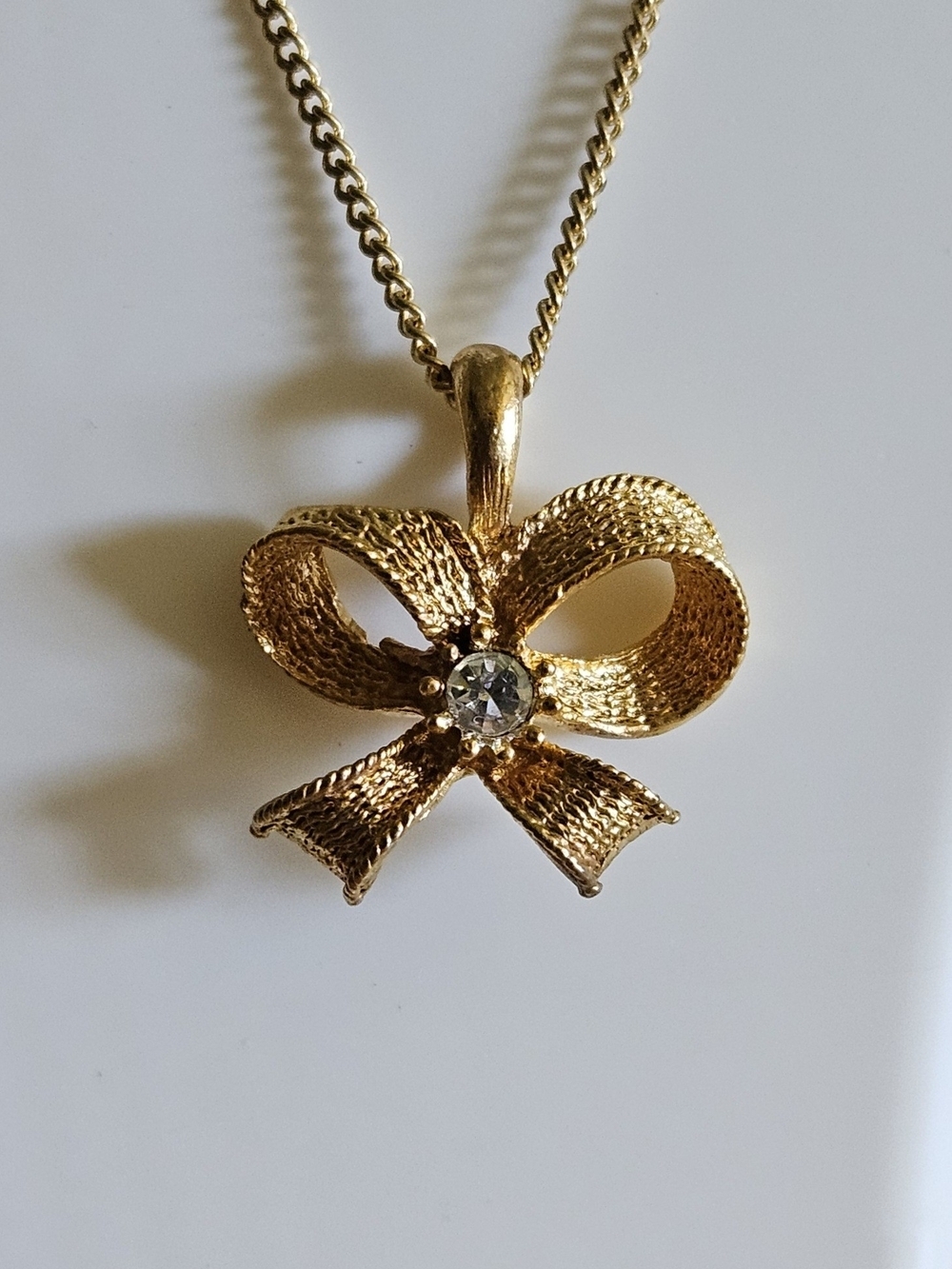 Gold Color Bow Pendant Necklace with Center Crystal.
